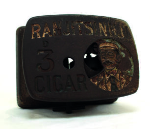 &lsquo;Ranjitsinhji 3d Cigar&rsquo;. Large heavy cast iron cigar cutter, the metal top with portrait of Ranjitsinhji, head and shoulders, wearing cap, blazer and tie with the wording &lsquo;&rsquo;Ranjitsinhji 3d Cigar&rsquo; to side. Wind-up mechanical mechanism beneath. &lsquo;Patent numb