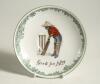 &lsquo;Good for Fifty&rsquo; Royal Doulton Black Boy saucer, entitled &lsquo;Good for Fifty&rsquo; printed with a boy in red shirt and a floppy hat in batting pose in front of the wicket to centre. Green floral decoration to edge. 5.5&rdquo; diameter. Doulton backstamp and number &lsquo;E43