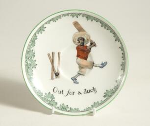 &lsquo;Out for a Duck&rsquo; Royal Doulton Black Boy saucer, entitled &lsquo;Out for a Duck&rsquo; printed with a boy in red shirt and a floppy hat in batting pose having attempted a big shot, looking back to see the ball hit his wicket. Green floral decoration to edge. 5.5&rdquo; dia