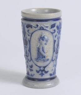 Westerwald stoneware cricket beaker, moulded in relief with three cameo panels of a batsman, after W.G. Grace, in different poses. The body highly decorated with vine and sprig decoration in cobalt blue on a grey background, with the figures highlighted i