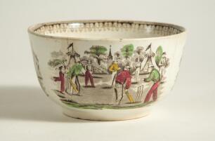 Village cricket bowl. Staffordshire 19th century bowl, transfer printed in black with three scenes of village cricket, with church and tents to background, floral and oak leaf inner rim decoration. Hand coloured in green, burgundy, and yellow. Approximat