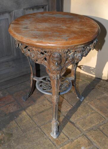 W.G. Grace. Original cast iron circular public house table with circular wooden top, supported by three legs, moulded with portrait busts of Grace wearing cricket cap to top of each leg with imprinted initials &lsquo;W.G&rsquo; above, and decorative pierced apron cen