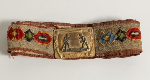Cricket belt. Early and complete material belt with oblong shaped brass belt buckle showing a bowler and batsman to centre with border decoration of cricket bats, balls, stumps, pads and gloves. The buckle measures approximately 2.25&rdquo;x1.75&rdquo;, the belt with