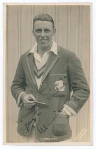 Maurice William Tate. Sussex & England 1912-1937. Early original sepia real photograph postcard of Tate standing three quarter length wearing cricket attire and M.C.C. tour blazer, pipe in hand. Signed in black ink &lsquo;Maurice Tate&rsquo; to the image. Printed tit
