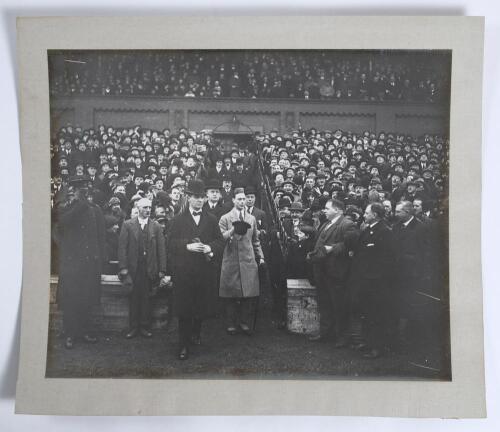 King George VI 1930s. A large original mono photograph of King George VI entering the field of an unknown sports stadium from a grandstand accompanied by dignitaries wearing formal attire and bowler hats. In the stands, large crowds are looking on enthusi