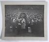 King George VI 1930s. A large original mono photograph of King George VI entering the field of an unknown sports stadium from a grandstand accompanied by dignitaries wearing formal attire and bowler hats. In the stands, large crowds are looking on enthusi
