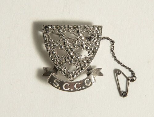 Sussex County Cricket Club pin badge. The silver and marcasite badge with Sussex emblem of the six martlets with &lsquo;S.C.C.C.&rsquo; below. Silver hallmarks for 1975. Complete with safety chain.