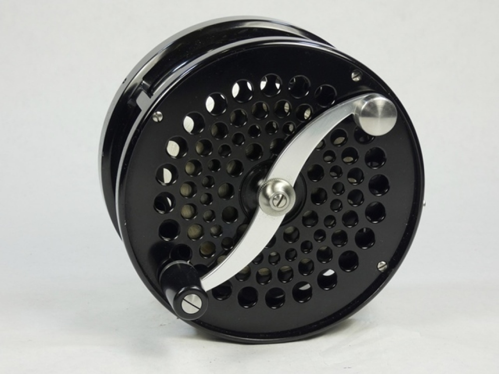 A fine Saracione Mk.IV Alta 4 ¾ salmon fly reel, left hand wind model with  black anodised finish, counter-balanced serpentine crank handle, alloy  foot, multi-perforated drum and face plate, rear sliding optional