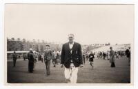 Scarborough Cricket Festival 1956. Mono real photograph plain back postcard of Johnny Wardle walking off the pitch wearing cricket attire and blazer, spectators milling around on the outfield in the background. Match unknown. Assumed to be by Walkers Stud