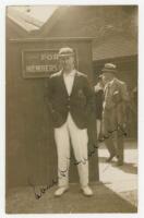 Ernest Tyldesley. Lancashire & England 1909-1936. Sepia real photograph postcard of Tyldesley standing full length at the members' entrance wearing Lancashire blazer and cap. Very nicely signed in ink to the image. Publisher unknown. Postally unused. Smal