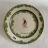 'Next Man In'. A Royal Doulton 'Black Boy' bone china dinner plate, entitled 'Next Man In' printed with a boy in red shirt and a floppy hat, sitting on his bat, waiting to go in. Green floral decoration to inner and outer rim. 10.25" diameter. Doulton bac