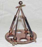 Cricket condiment stand. Silver metal 'EPNS' condiment stand comprising circular base on four decorative floral feet, with four sloping cricket bats, each resting on a ball, surmounted by a further ball. Date and maker unknown. 6.5" tall. Some tarnishing,