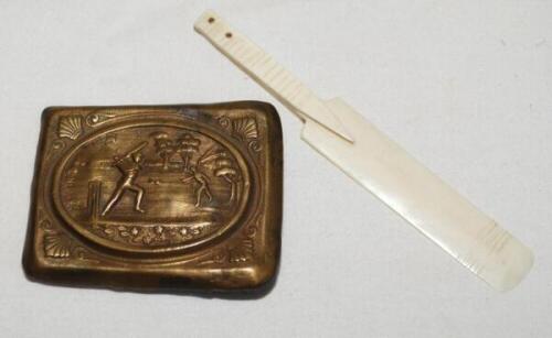 Cricket belt buckle. An attractive Victorian brass buckle with impressed image of a cricket match in progress to centre with cartouche surround. 2.25"x1.75". Sold with a miniature ivory cricket bat. 4" long. Qty 2. G - cricket