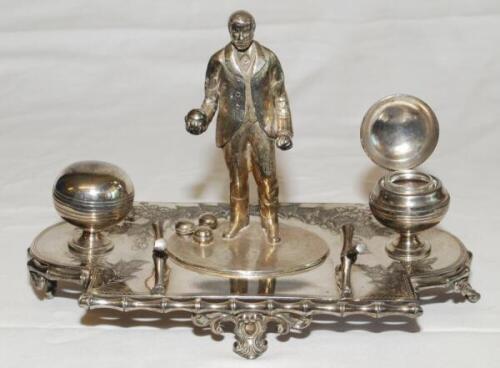 Lawn bowls. Silver metal (EPNS) ink stand of a 'bowler' standing holding a ball with three more balls at his feet. To either side, two inkwells in the form of bowling balls, one with glass liner, and foliage decoration. Maker's mark to underside for 'J.D.