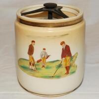 Golf tobacco jar. Carlton Ware jar with removable cover c.1910s/1920s. To one side a colour transfer image of two gentlemen playing golf with a caddy, to the reverse, a crossed clubs emblem with golf ball and scroll inscribed 'Far and Sure'. 5" tall. Carl