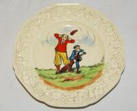 Golfing plate with humorous hand painted golfing scene. Floral and fruit decoration to rim, scalloped edges. Crown Ducal Florentine. 8" diameter. Sold with a packet of 'Black Boy Brand' cricket and golf spikes in original decorative card box. Qty 2. G/VG