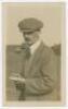 John 'Jack' White. Sepia real photograph postcard of white, half length wearing a cap, smoking a pipe and inspecting a card. Annotation to verso suggests the photograph was taken at Sunningdale. Date and publisher unknown. VG