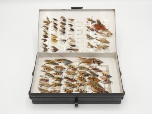 A Malloch black japanned salmon fly reservoir the rectangular cantilevered opening case with four fly compartments each fitted bars of nickel silver spring clips and housing a collection of 108 fully dressed salmon flies and loch patterns including 31 gut