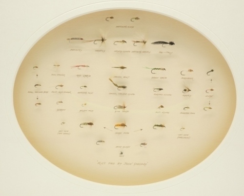 A good framed display of thirty six John Goddard tied trout flies and nymphs, mounted by Robin Armstrong within a recessed oval shadow mount and light wood frame, cream card backboard with ink inscribed pattern details, verso with further printed pattern 