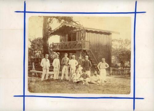 Victorian cricket. Early original albumen sepia photograph c.1870s depicting ten cricketers seated and standing in informal pose wearing cricket attire and assorted blazers and headgear. Behind the players is a two storey wooden chalet style pavilion in a