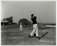 Peter Thomson. Mono copy press photograph of Thomson driving on the practice ground, a young boy in the background looking on. Signed in bold black ink to the photograph by Thomson. 10&quot;x8&quot;. VG - golf