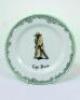 'The Boss'. A Royal Doulton Black Boy dessert plate, entitled 'The Boss' printed with a boy in red shirt and a floppy hat, wearing an umpires's coat and holding a bat,. Green floral decoration to outer rim. 7&quot; diameter. Doulton backstamp and number '