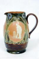 Cricketing jug. A large and impressive Doulton Lambeth stoneware jug, of bulbous form, with three moulded relief vignettes of cricketers, a batsman, bowler and wicket keeper, Abel, Woods and McGregor in white on a brown background. With stylised floral le