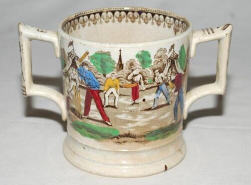 'Village cricket'. A Victorian Staffordshire loving cup, printed in black/brown with two different scenes of village cricket, with church and tents to background, floral and oak leaf rim decoration and crossed cricket bats, balls and stumps decoration to 