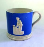 Staffordshire blue cricket mug. Staffordshire ground straight sided mug, in blue with white base, with strap handle and two relief moulded figures of a batsman and bowler in white, believed to be Pilch and Clarke. c1860. Very minor chip close to rim other
