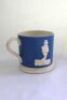 Staffordshire blue cricket mug. Staffordshire ground straight sided mug, in blue with white base, with strap handle and two relief moulded figures of a batsman and bowler in white, believed to be Pilch and Clarke. c1860. Very minor chip close to rim other - 2