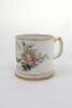Cricket mug/cup. A white ceramic mug with central image of a cricket wicket, bat and ball with inscription above and below 'Blanche Hibbard. Veni Vici July 1879'. This floral rose design to borders. Gold lustre to base, rim and handle. The mug stands 3.25 - 2