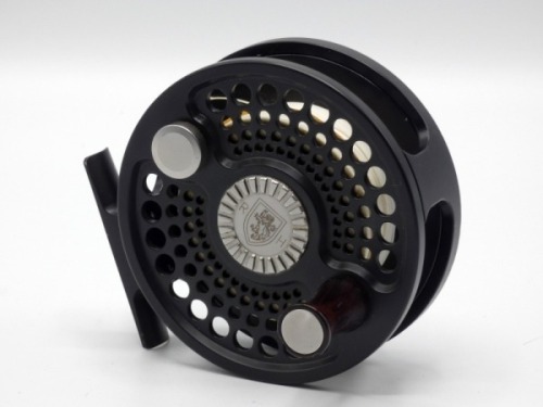 A rare Charlton Thinn-Line Series model 8500 #8 bonefish/trout fly reel, black satin finish right hand wind model, drum with perforated front plate, counter-balanced waisted rosewood handle and grooved circular alloy spool release disc, rear spindle mount