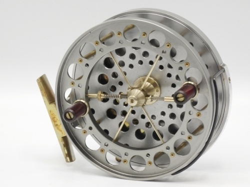 A fine Mills Tackle Co. Barbel Catcher 4 1/2" centre pin reel, caged and six spoked drum with twin rosewood handles, ventilated front and rear plates and twin regulator/release forks, B.P. line guide, brass stancheon foot, rim mounted optional check leve