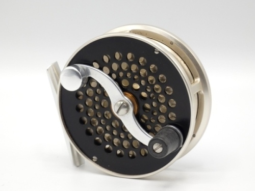 A good S.E. Bogdan Trout 5wt fly reel, left hand wind model with light champagne/black anodised finish, counter-balanced composition handle on serpentine crank winding arm set within an anti-foul rim, pierced alloy foot, multi-perforated front drum and f