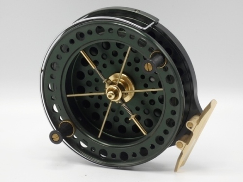 A J.W. Young’s John Wilson Heritage 4 1/2" narrow drummed trotting reel, green anodised finish, shallow cored drum with twin composition handles, six cage spokes and twin release/regulator forks, wire B.P. line guide, brass foot, rear optional check leve