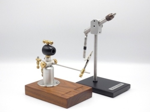 A fine Dyna-King “Squire" table fly tying vice, rectangular black steel base, clamp locking vice head with milled brass forcing cone, brushed steel shaft, as new condition and in original card box with paperwork and an un-named teak based table fly tying 