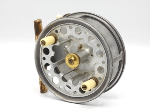 A rare Percy Wadham Carisbrooke 4" alloy bait casting reel, skeletal shallow drum with slotted core, twin ivorine handles and central brass milled locking nut, brass foot, rear plate with three large cut-away finger ports for drum braking, rim mounted bra