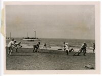 Cricket at sea. Original mono press photograph of an unusual game of cricket taking place on Gunfleet Sands off the Essex coast at low tide, with boats anchored in the background. Press caption to verso describes the match played by Walton and Frinton Yac