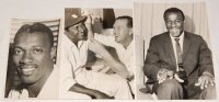 West Indies tour to Australia 1960/61. 'Tied Test' series. Two original mono press photographs from the 1960/61 series. One depicts local Melbourne M.P., Mac Holten, clipping a 'safety cord' to the cap of West Indian Joe Solomon in the dressing room at Me