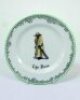 'The Boss'. A Royal Doulton Black Boy dessert plate, entitled 'The Boss' printed with a boy in red shirt and a floppy hat, wearing an umpires's coat and holding a bat,. Green floral decoration to outer rim. 7" diameter. Doulton backstamp and number 'E4336