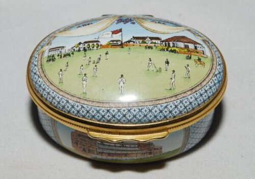 'Bicentenary of the M.C.C.'. Halcyon Days oval enamelled pill box. The lid with a cricket match at Lord's, the hinged lid revealing title 'To commemorate the Bicentenary of the Marylebone Cricket Club 1787-1987' and small vignette of Thomas Lord. The oute