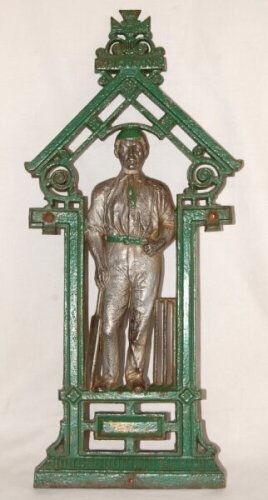 Cricket stick/umbrella stand. Green painted cast iron stick/umbrella stand in Victorian style. With figure of cricketer to centre, bat to right and stumps to left. The surround and cricketer's cap and tie painted in green. 'Cricketer' to emblem at top. La