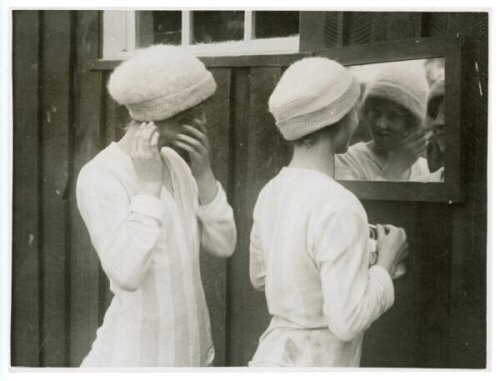 'Girl Footballers in Training for Their Cup' c.1930s. Original mono press photograph of two members of the Bramtoco (Southampton) ladies football team, both wearing woollen hats, preparing themselves in front of a mirror before a match. The press caption 