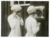 'Girl Footballers in Training for Their Cup' c.1930s. Original mono press photograph of two members of the Bramtoco (Southampton) ladies football team, both wearing woollen hats, preparing themselves in front of a mirror before a match. The press caption 