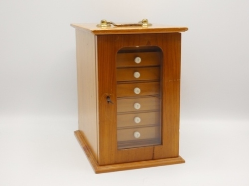 A rectangular pine salmon fly reservoir, fitted eight sliding drawers each with ivorine bun handle and fitted bars of nickel silver spring fly clips on ivorine plates, glazed door and brass swing carry handle, 9 ¾" x 9 ½" x 6 ½" overall