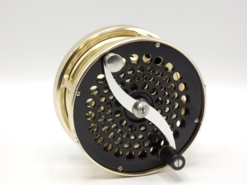 A fine Saracione Mk.IV Alta 4 ¾" salmon fly reel, left hand wind model with black /gold anodised finish, counter-balanced serpentine crank handle, alloy foot, multi-perforated drum and face plate, rear sliding optional check button and spindle mounted mil