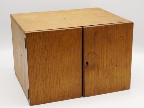 An Edwardian rectangular oak fly-tying chest, twin doors opening to reveal five interior drawers, the two lower with recessed brass handles, lift-out lower tray, lidded and open tool/material compartments and the three upper drawers with steel hook fly lo