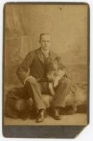 Pelham Francis ‘Plum’ Warner. Oxford University, Middlesex & England 1894-1920. Original sepia cabinet card studio photograph of a youthful Warner seated, full length in formal attire, with a dog on his lap. Photograph by Jas. Soane Jnr., Oxford c. 1895. 