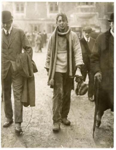 Eton Wall Game c.1920s. Two original mono press photographs, one depicting an Etonian full length in attire including striped woollen scarf and carrying a matching hat, surrounded by smartly dressed onlookers wearing suits and headgear of the period. Penc