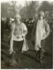 Eton Wall Game c.1920s. Two original mono press photographs, one depicting an Etonian full length in attire including striped woollen scarf and carrying a matching hat, surrounded by smartly dressed onlookers wearing suits and headgear of the period. Penc - 3